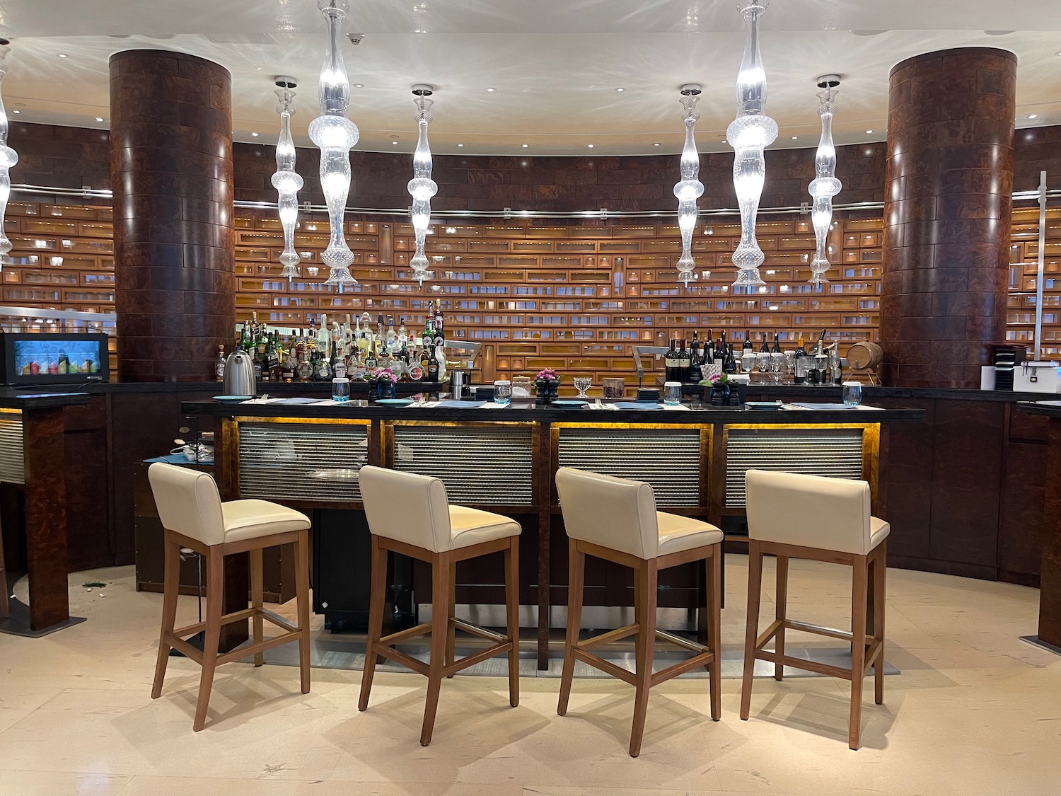 a bar with chairs and a bar with lights from the ceiling