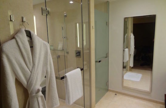 a bathroom with a white robe and a glass shower door