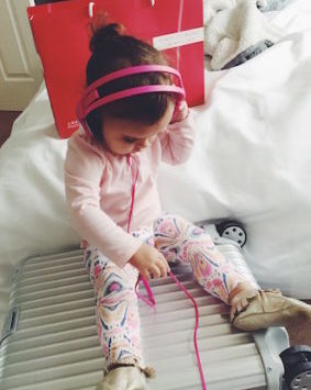 a child wearing headphones sitting on a suitcase