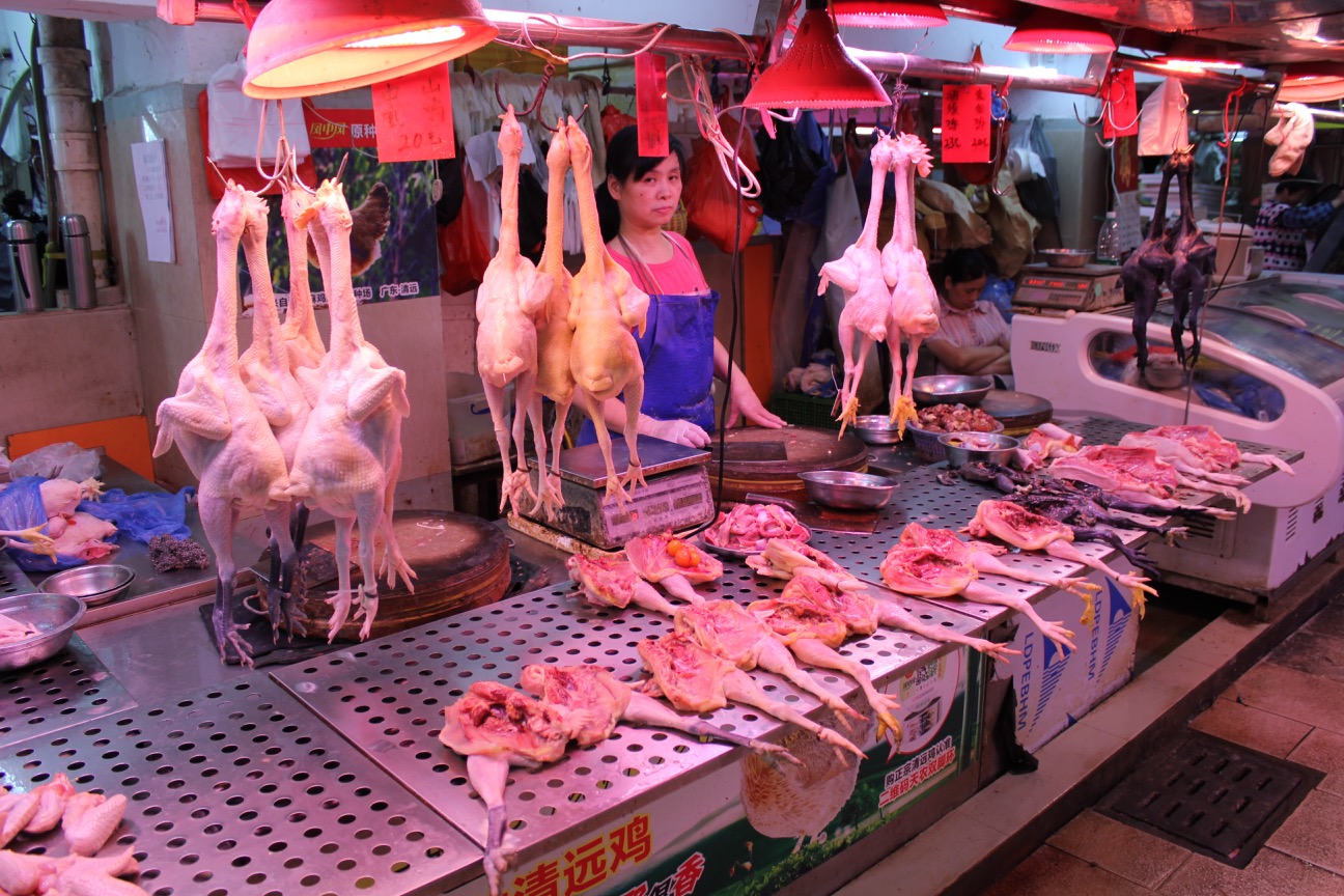 a woman selling raw chicken in a market