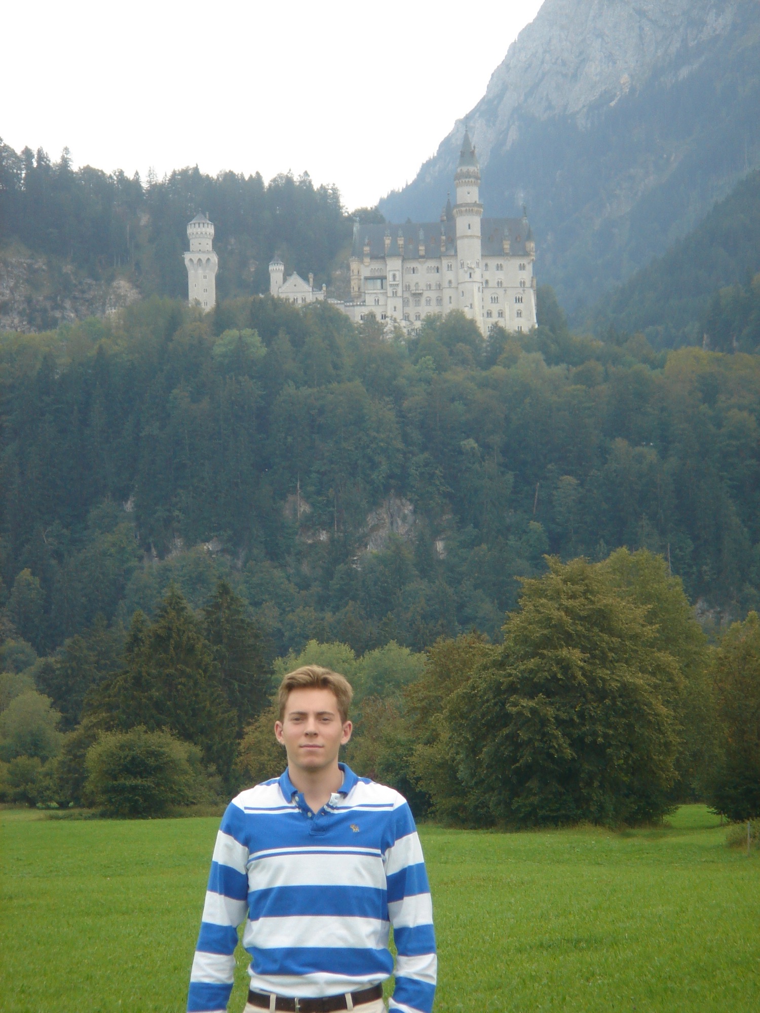 a man standing in a field with a castle in the background