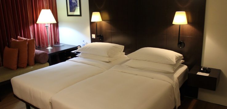 a two beds with white sheets and lamps in a room
