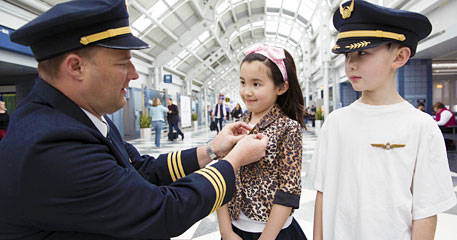 a man in uniform putting on a girl's shirt
