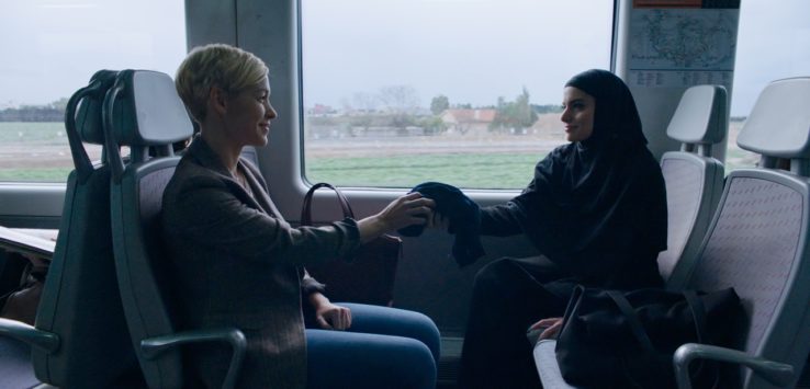 a woman sitting in a bus with a woman in a head scarf