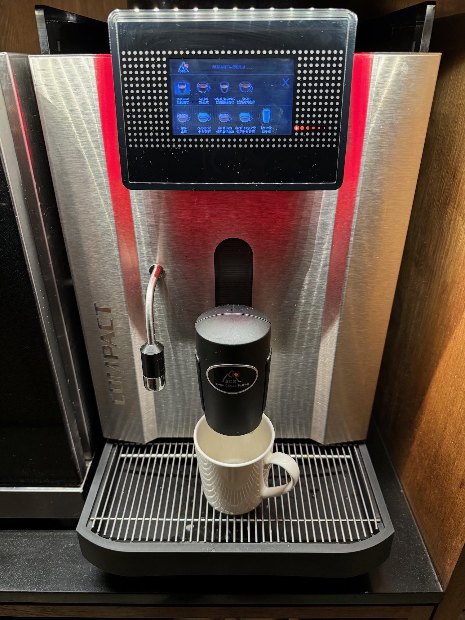 a coffee machine with a screen and a cup on a grate