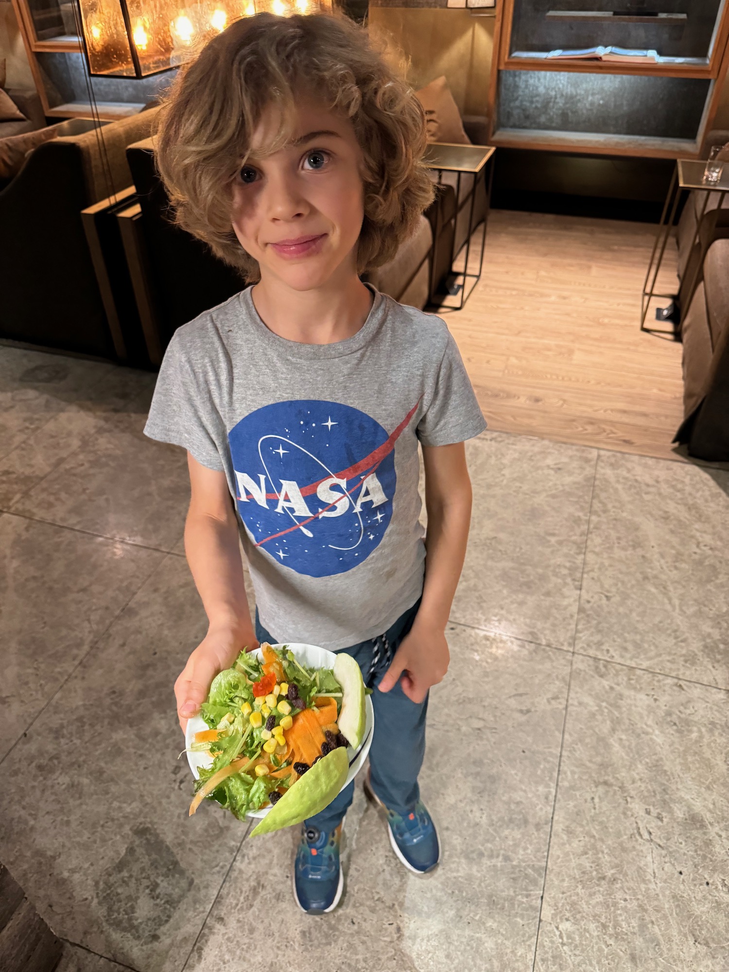 a boy holding a bowl of salad