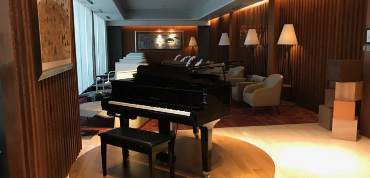 a piano on a circular platform in a room with chairs and a wall