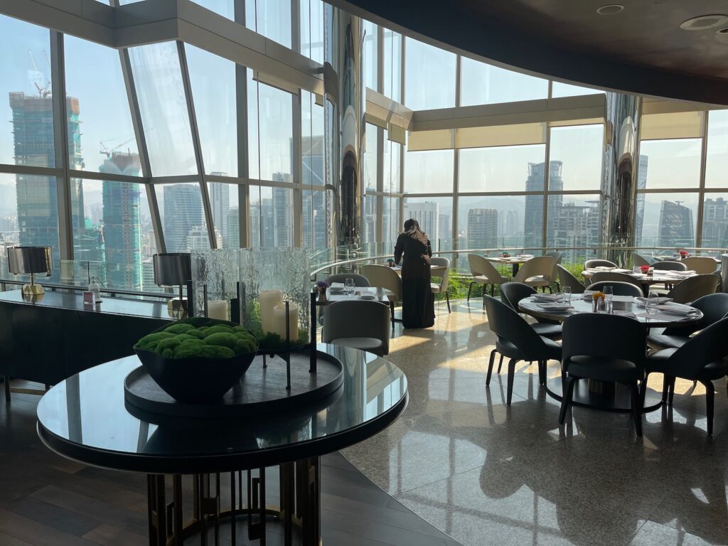 a room with a view of a city and a woman standing in front of the window