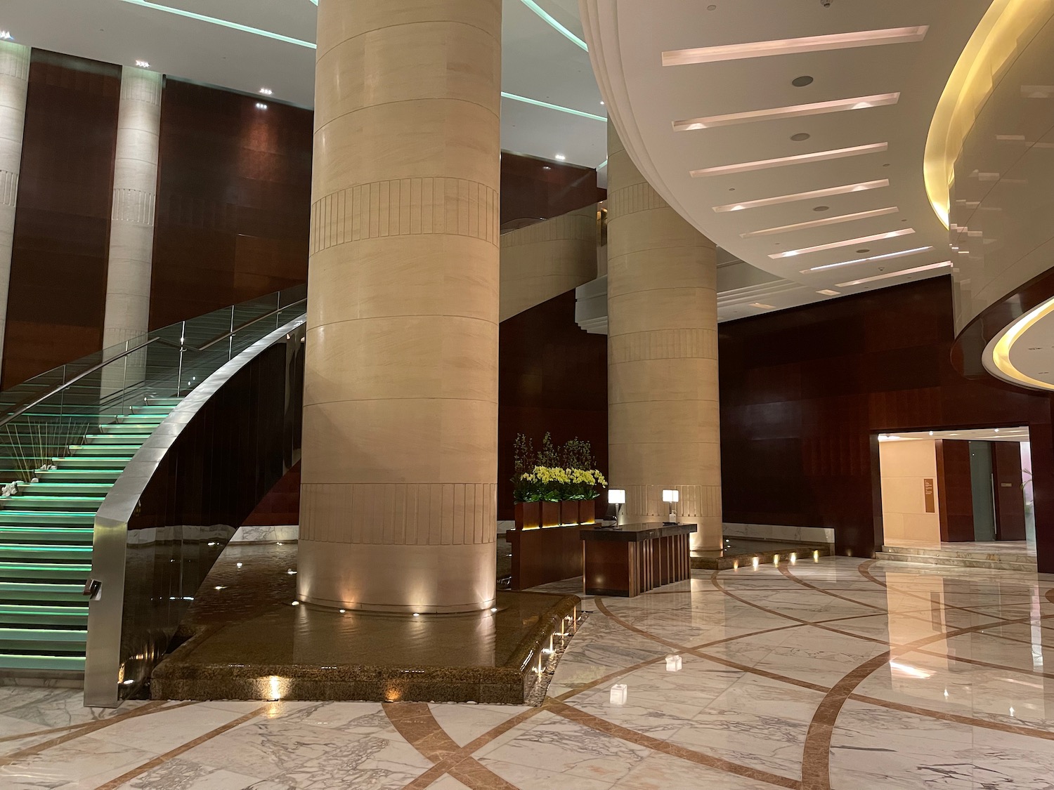 a large marble floor with a staircase and a large column