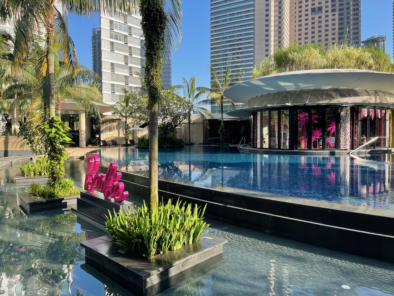 a pool with plants and trees in front of a building