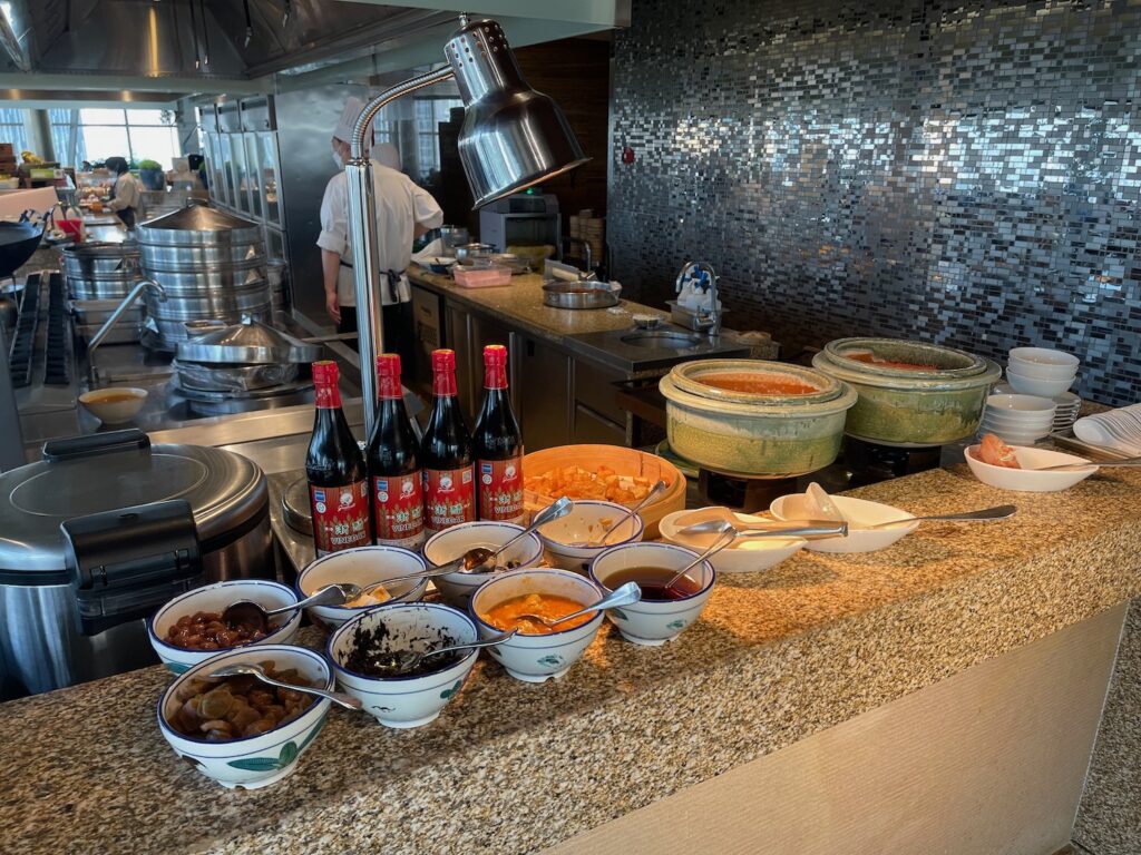 a counter with bowls of food and bottles of sauce