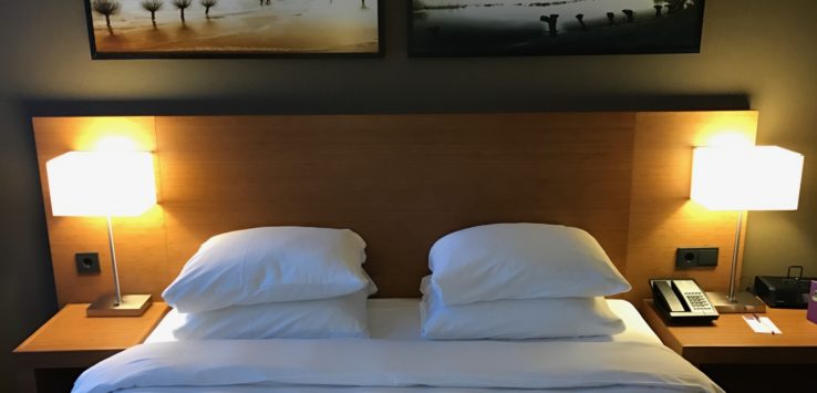 a bed with white sheets and lamps