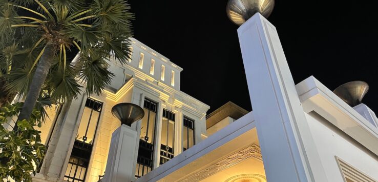 a white building with a chandelier and palm trees