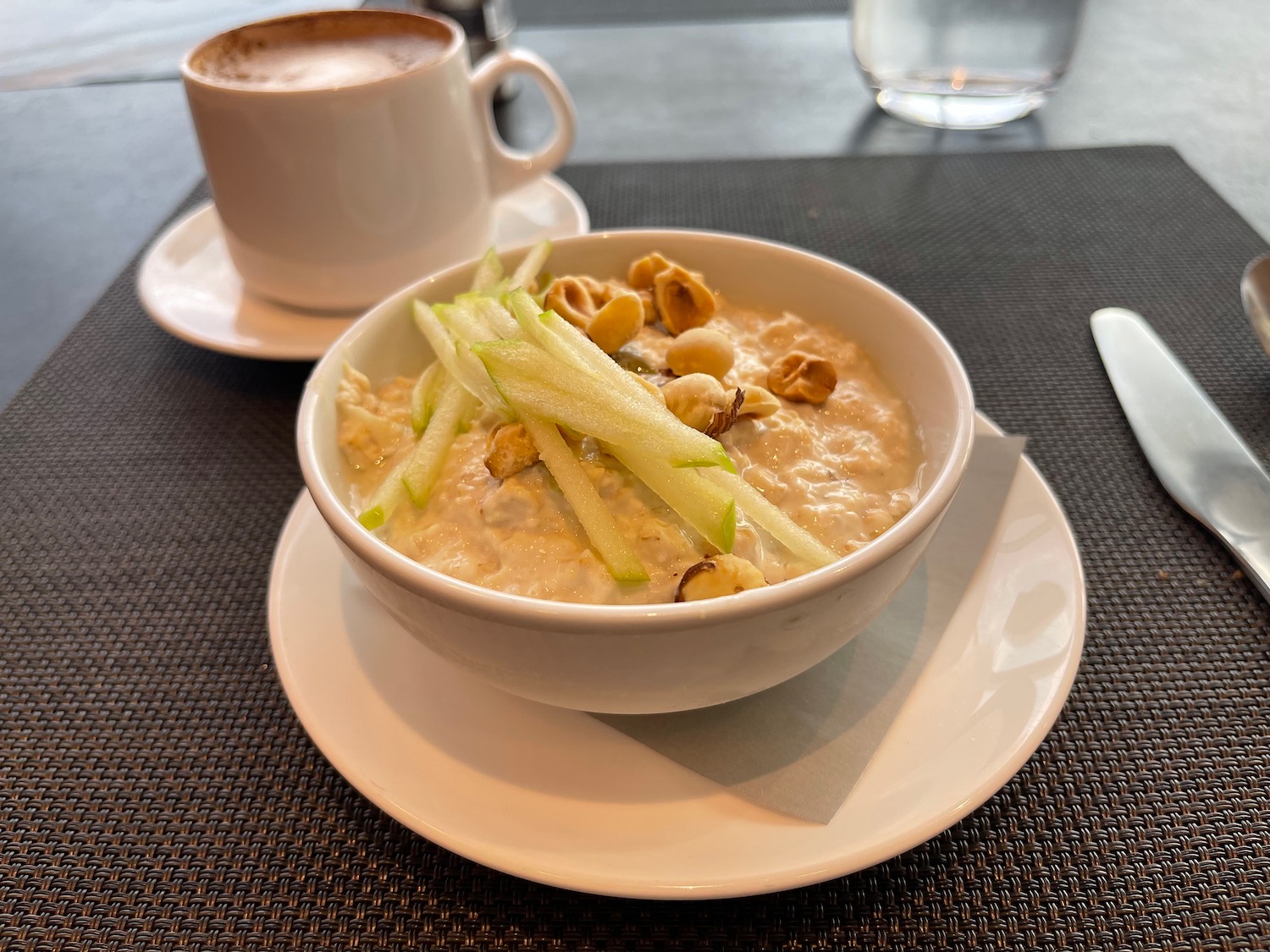 a bowl of oatmeal with nuts and a cup of coffee