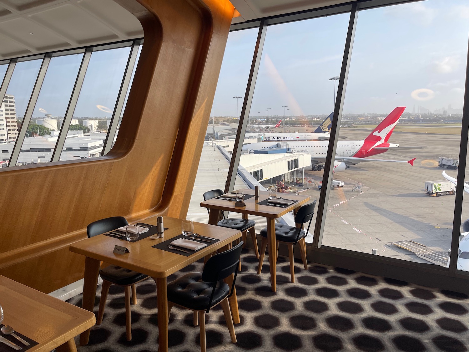 a table and chairs in a room with windows and planes in the background