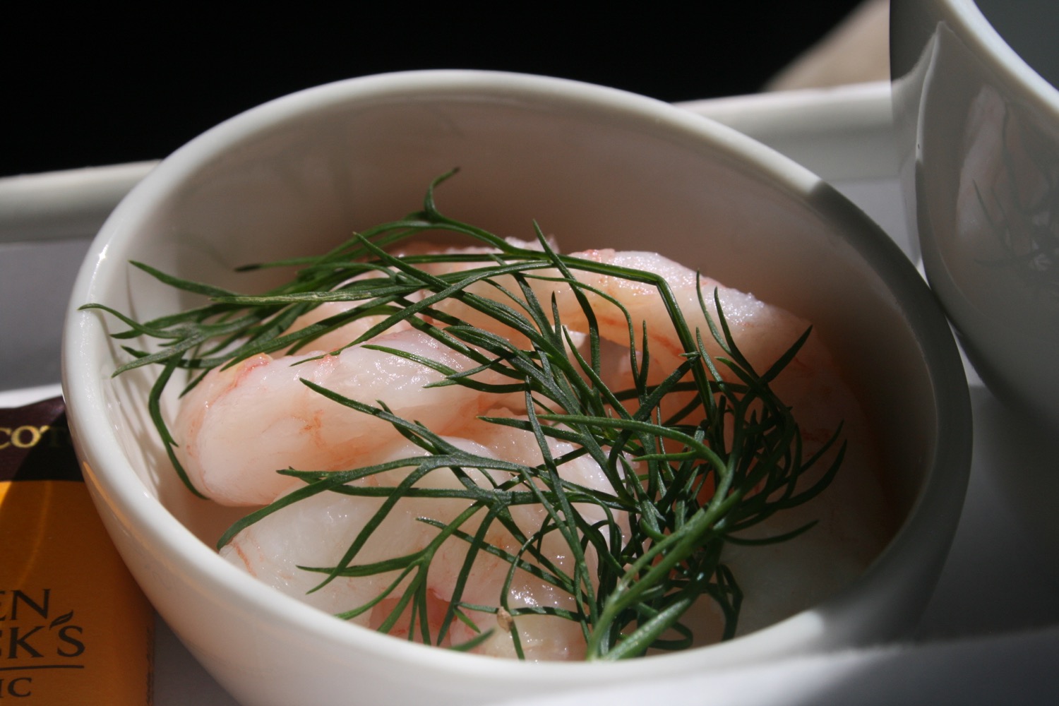 a bowl of shrimp with a green sprig of dill