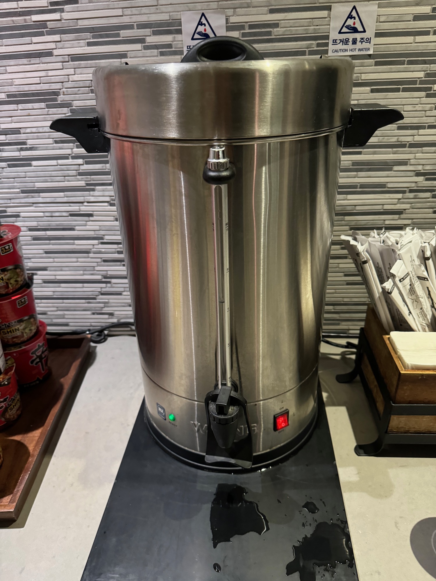 a large stainless steel container with a black lid