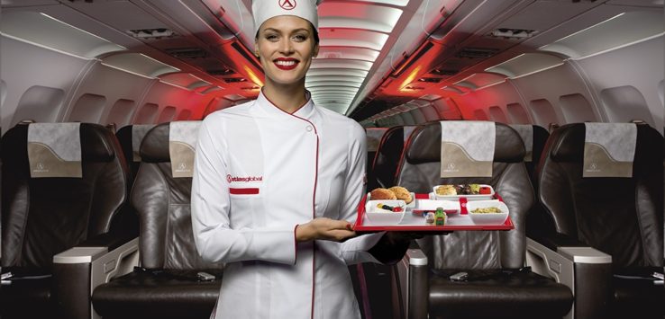 a woman in a chef uniform holding a tray of food