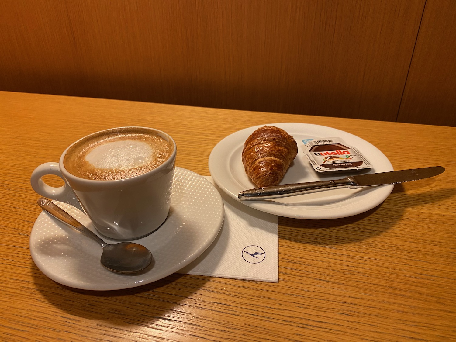 a cup of coffee and a croissant on a plate
