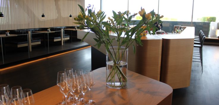 a vase of flowers on a table with wine glasses