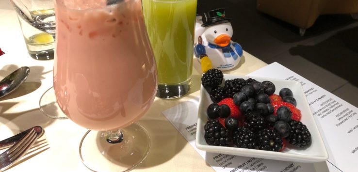 a glass of fruit juice and a bowl of fruit