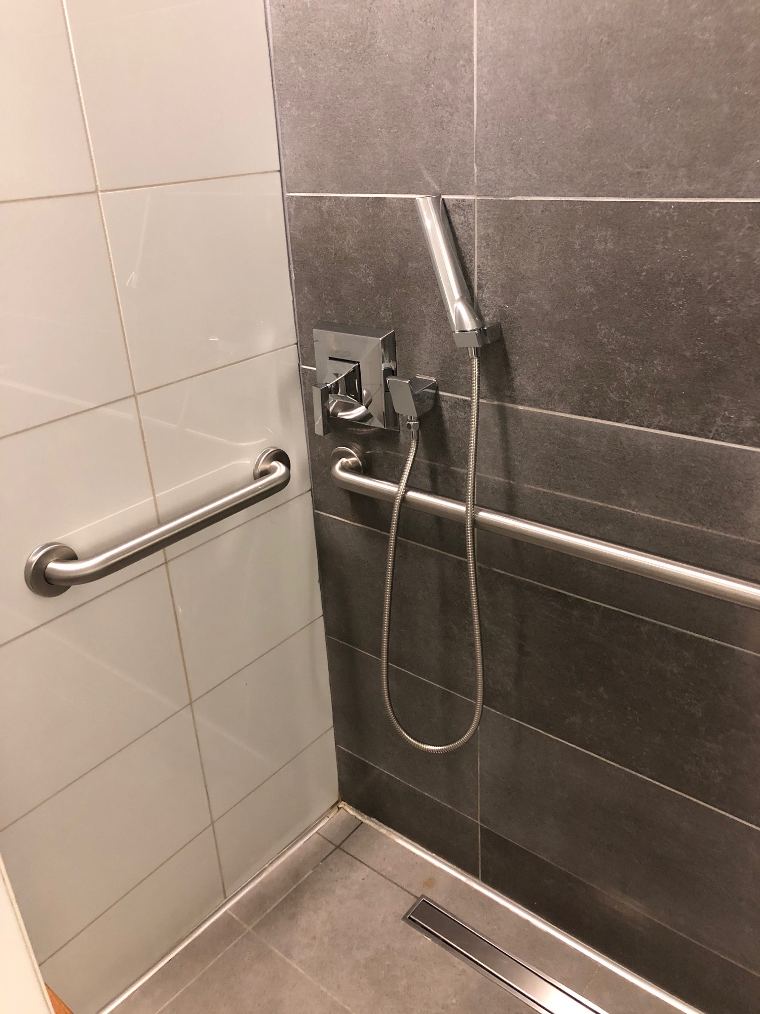 a shower with a hand rail and a shower head