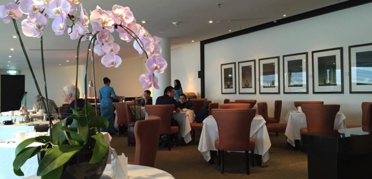 a room with tables and chairs and a vase of flowers