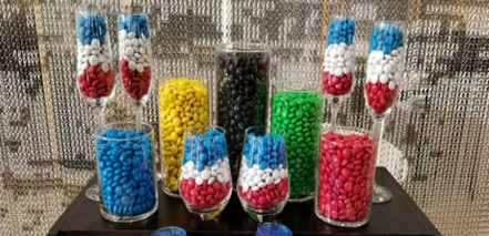 a group of glasses filled with different colored candies
