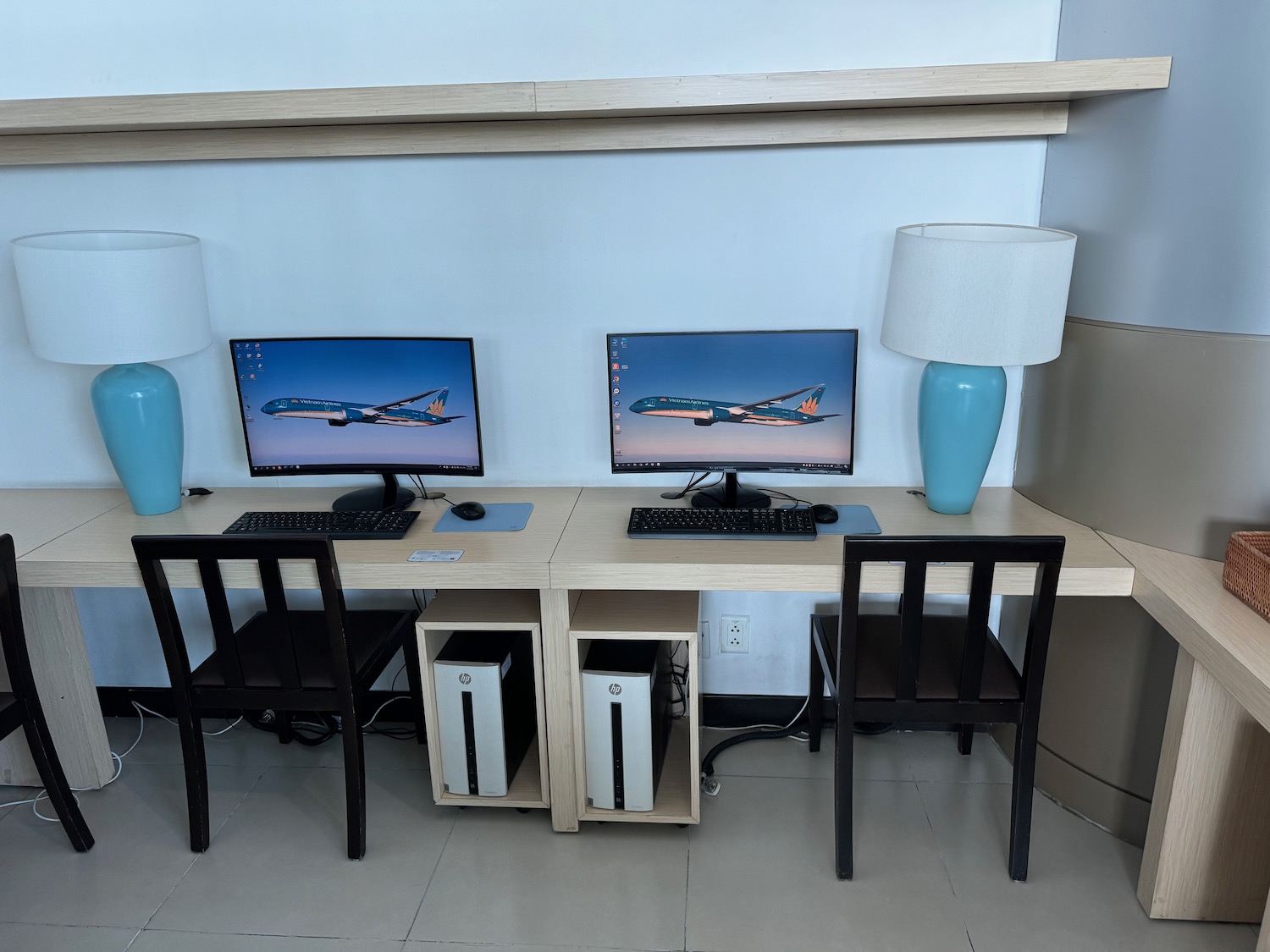 a desk with two computers and a lamp