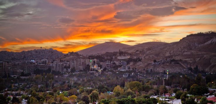 a city with trees and mountains in the background