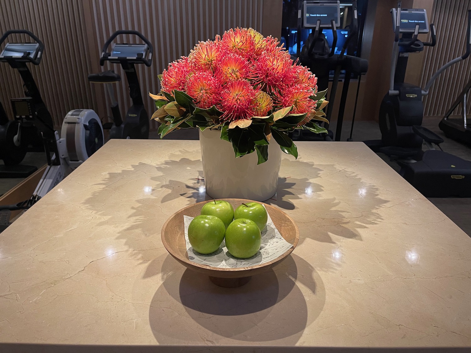 a bowl of apples and a vase of flowers on a table