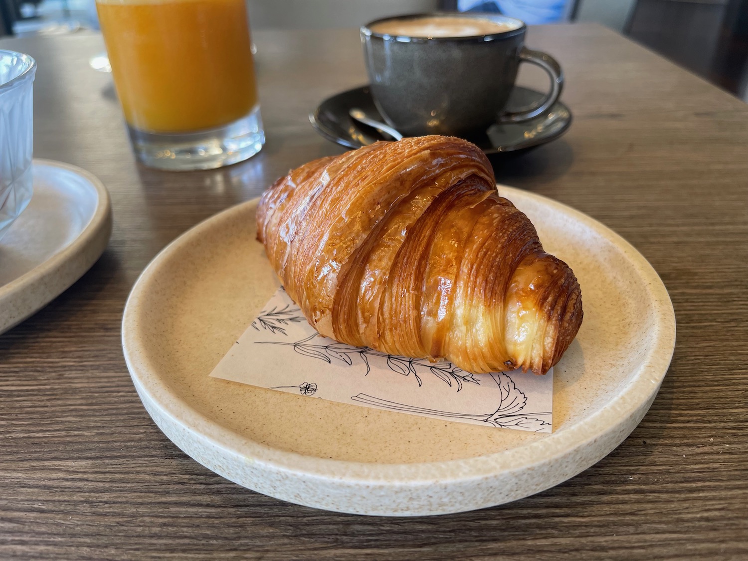 a croissant on a plate next to a cup of coffee