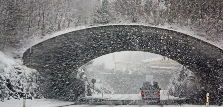 a car driving under a bridge in the snow