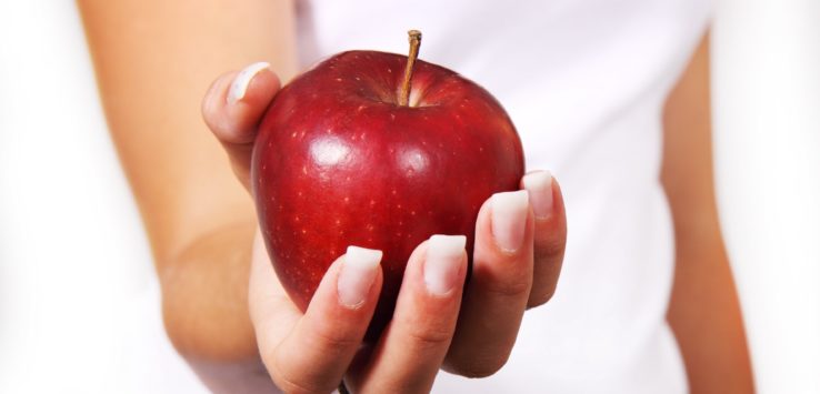 a hand holding a red apple