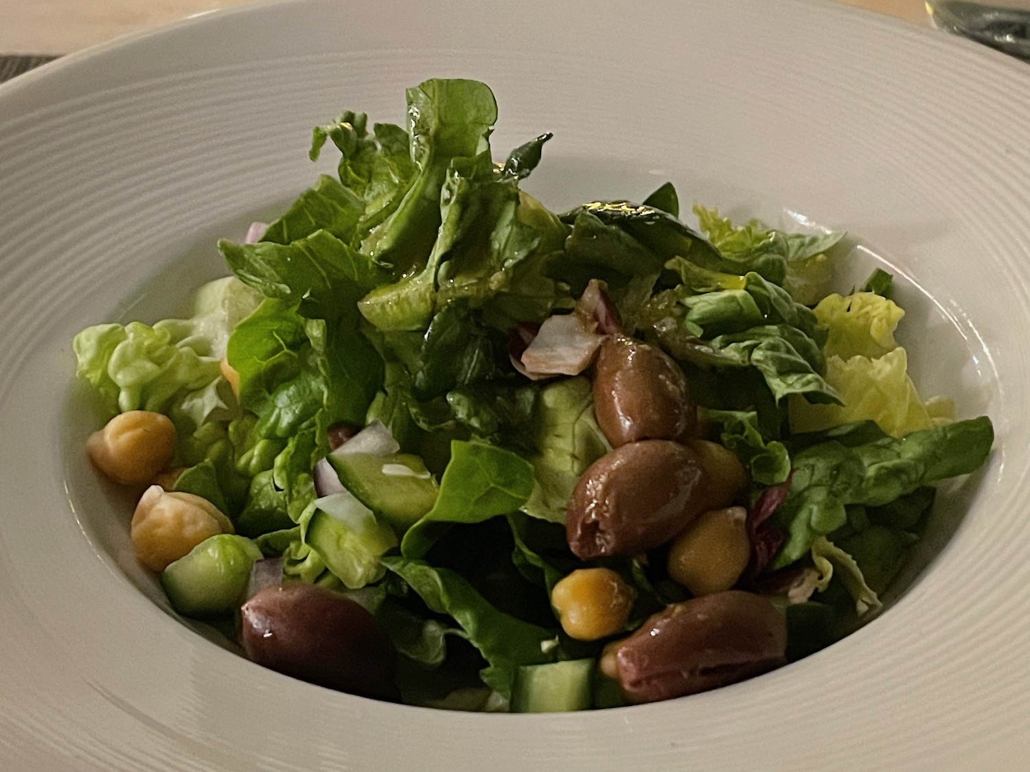 a bowl of salad with olives and lettuce