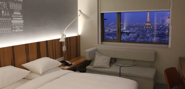 a bedroom with a bed and a window with a view of the eiffel tower