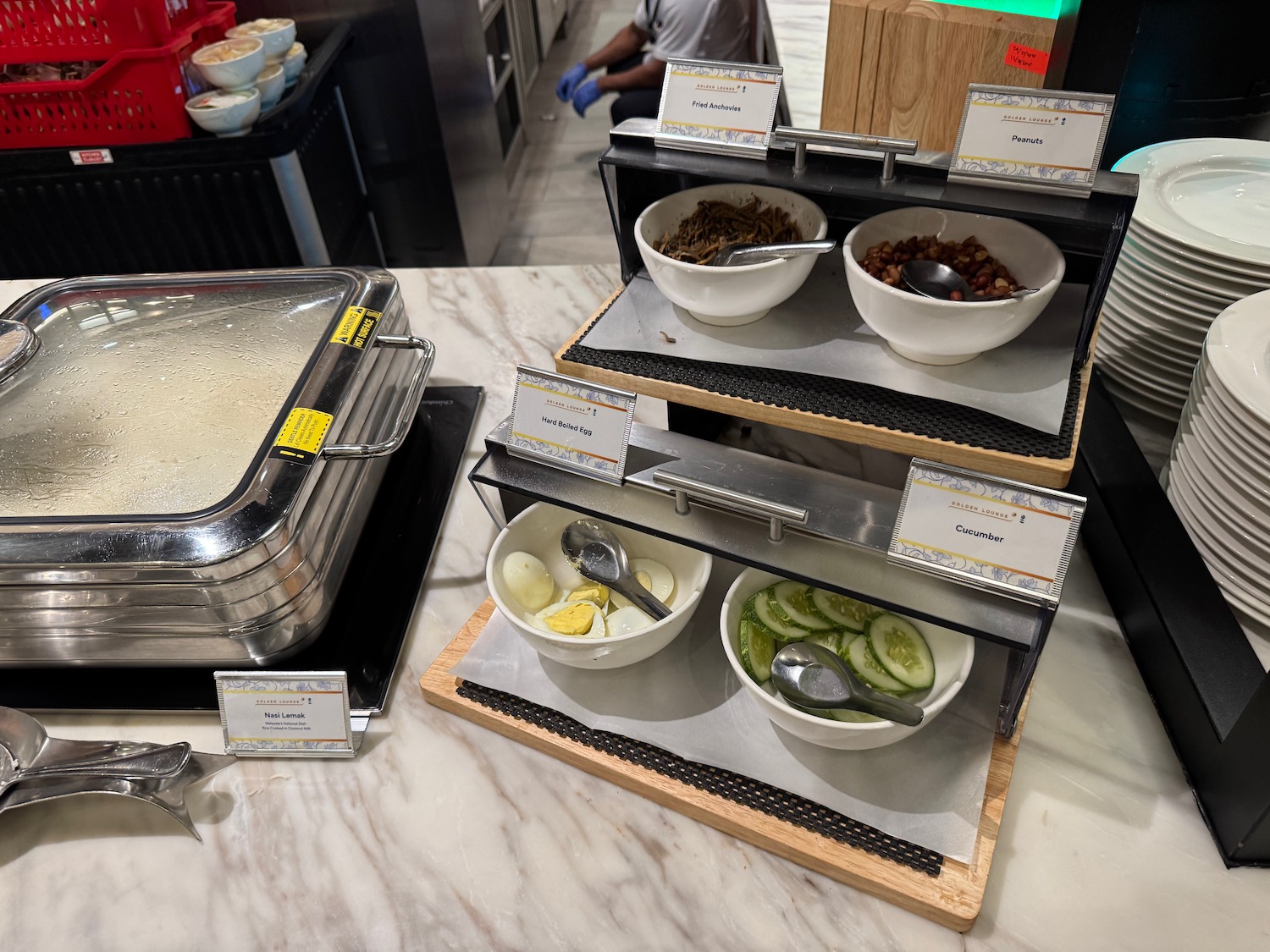 a buffet line with bowls of food and spoons