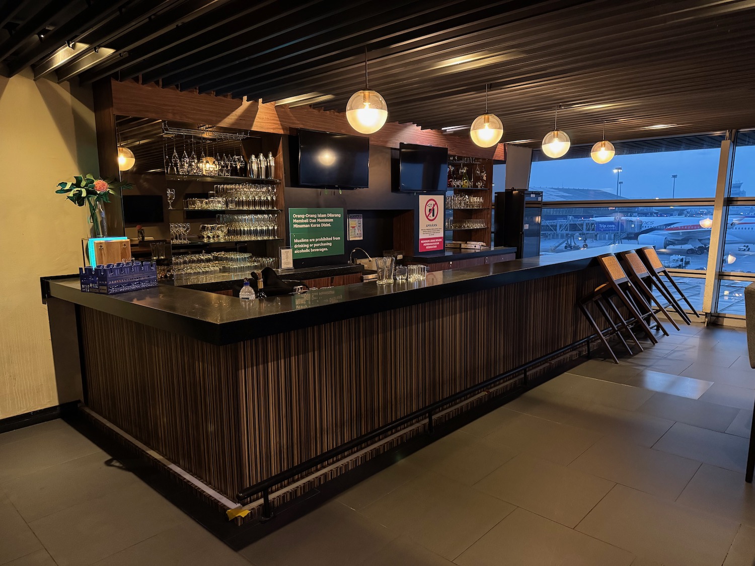 a bar with a glass shelf and chairs