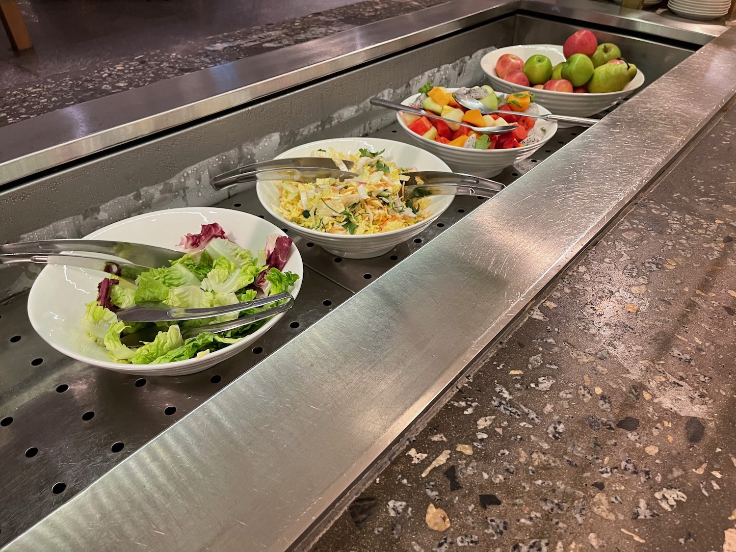 a row of bowls of salad and fruit