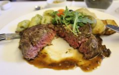 a plate of food with a cut piece of meat and vegetables