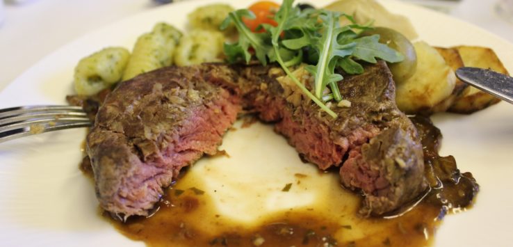 a plate of food with a cut piece of meat and vegetables