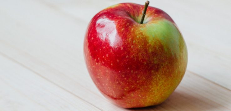 a red and green apple on a wood surface