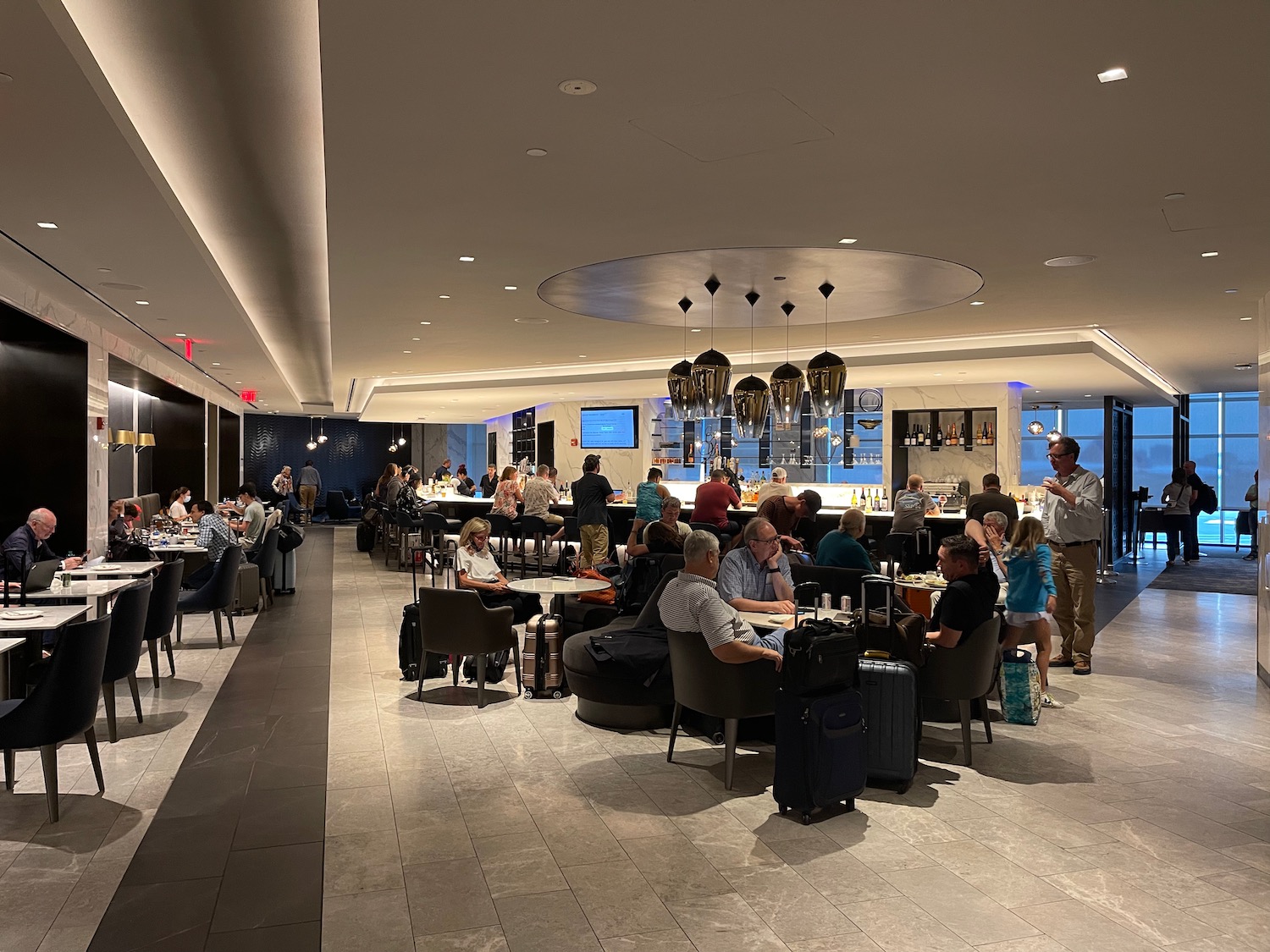 a group of people sitting at tables in a room with luggage