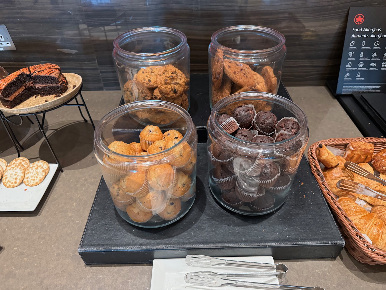 a group of glass containers of cookies and muffins