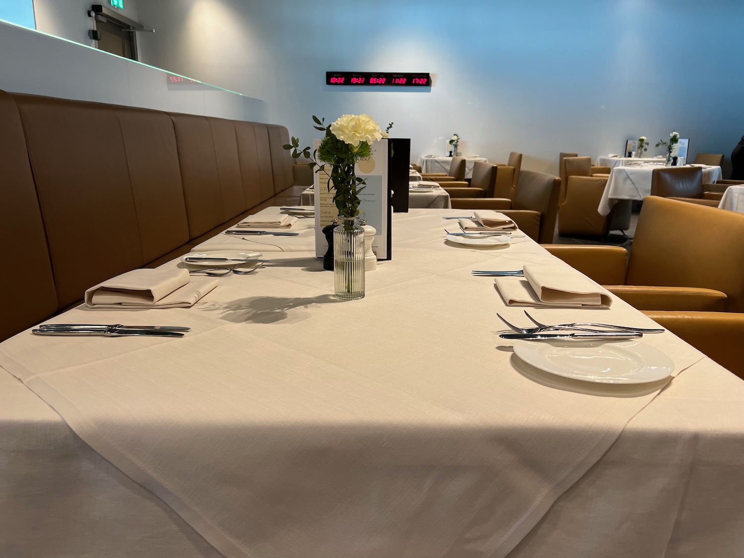 a table with white tablecloths and white plates and a vase of flowers