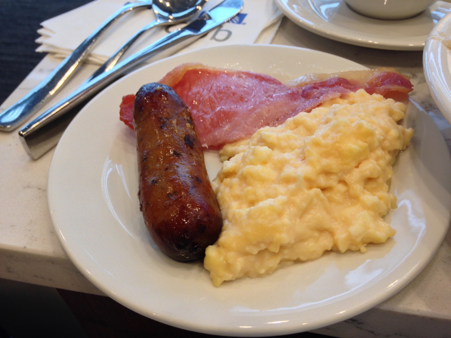 a plate of food with a sausage and scrambled eggs