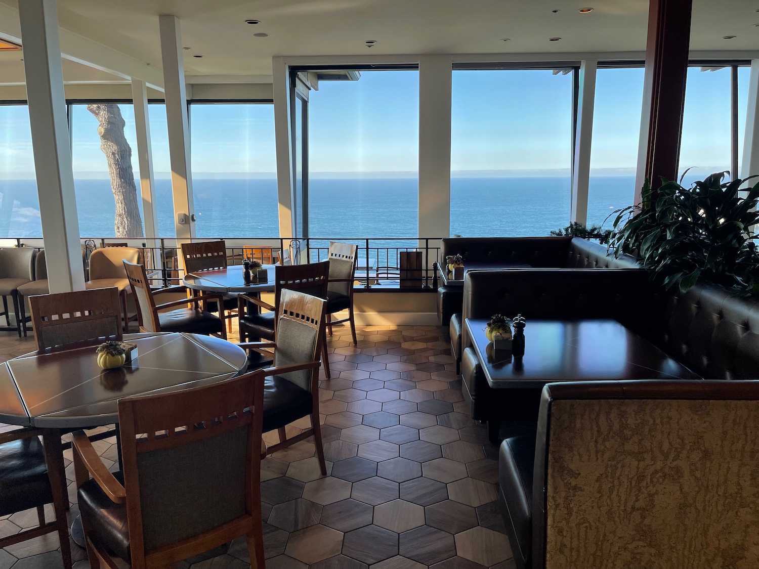 a room with tables and chairs and a view of the ocean