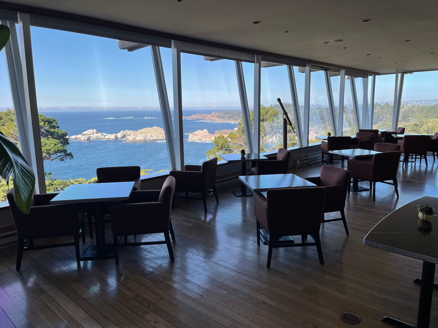 a room with tables and chairs and a large window overlooking water