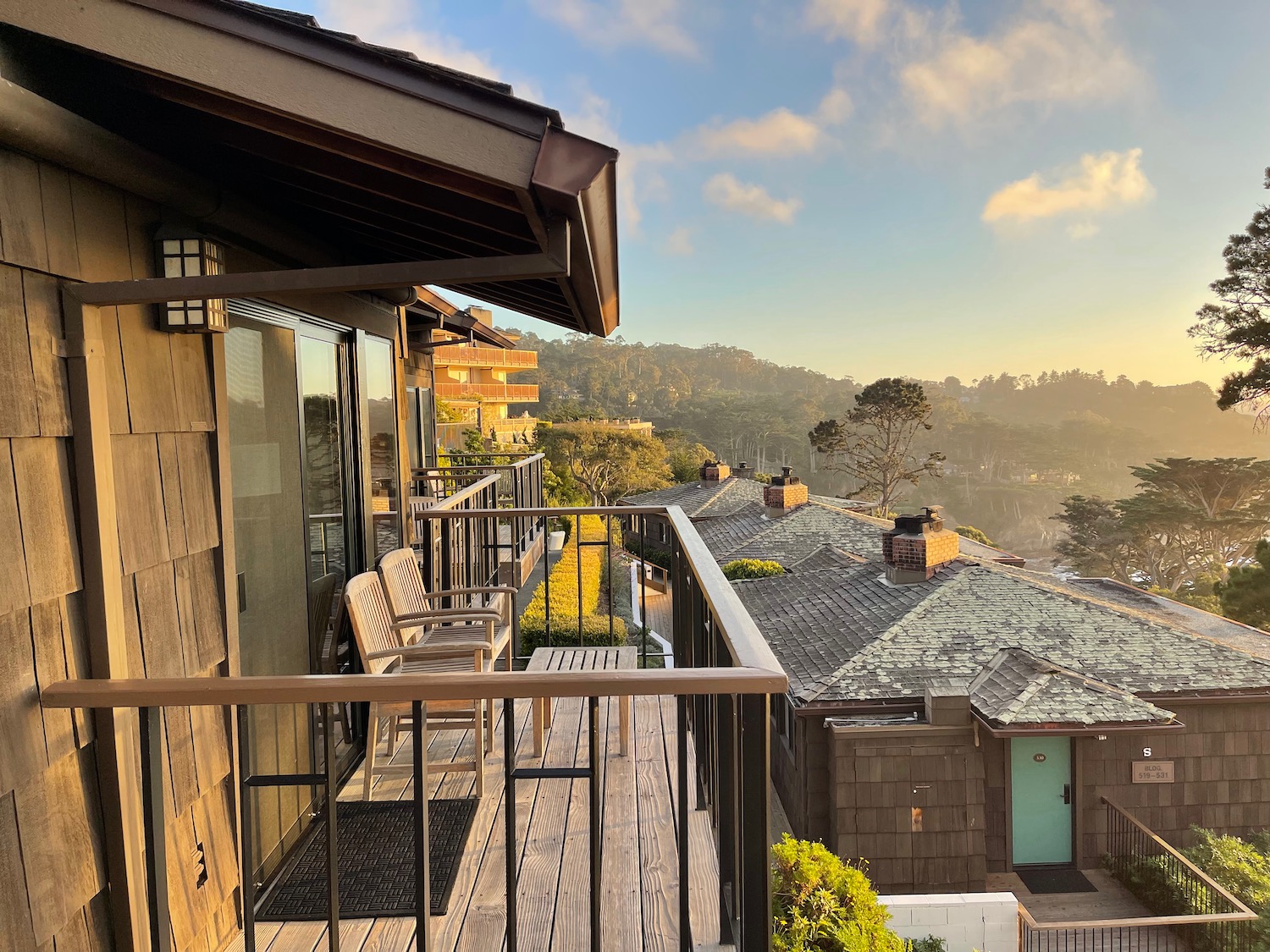 a balcony with chairs and a railing overlooking a mountain range