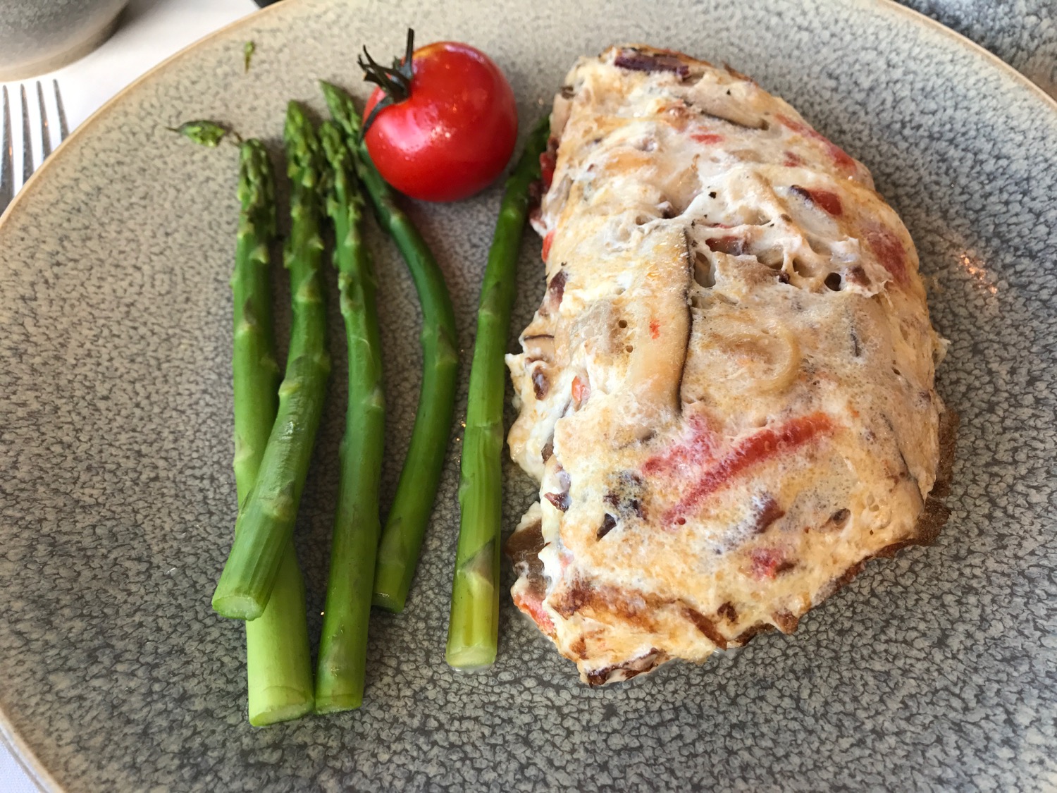 a plate of food with a tomato and asparagus